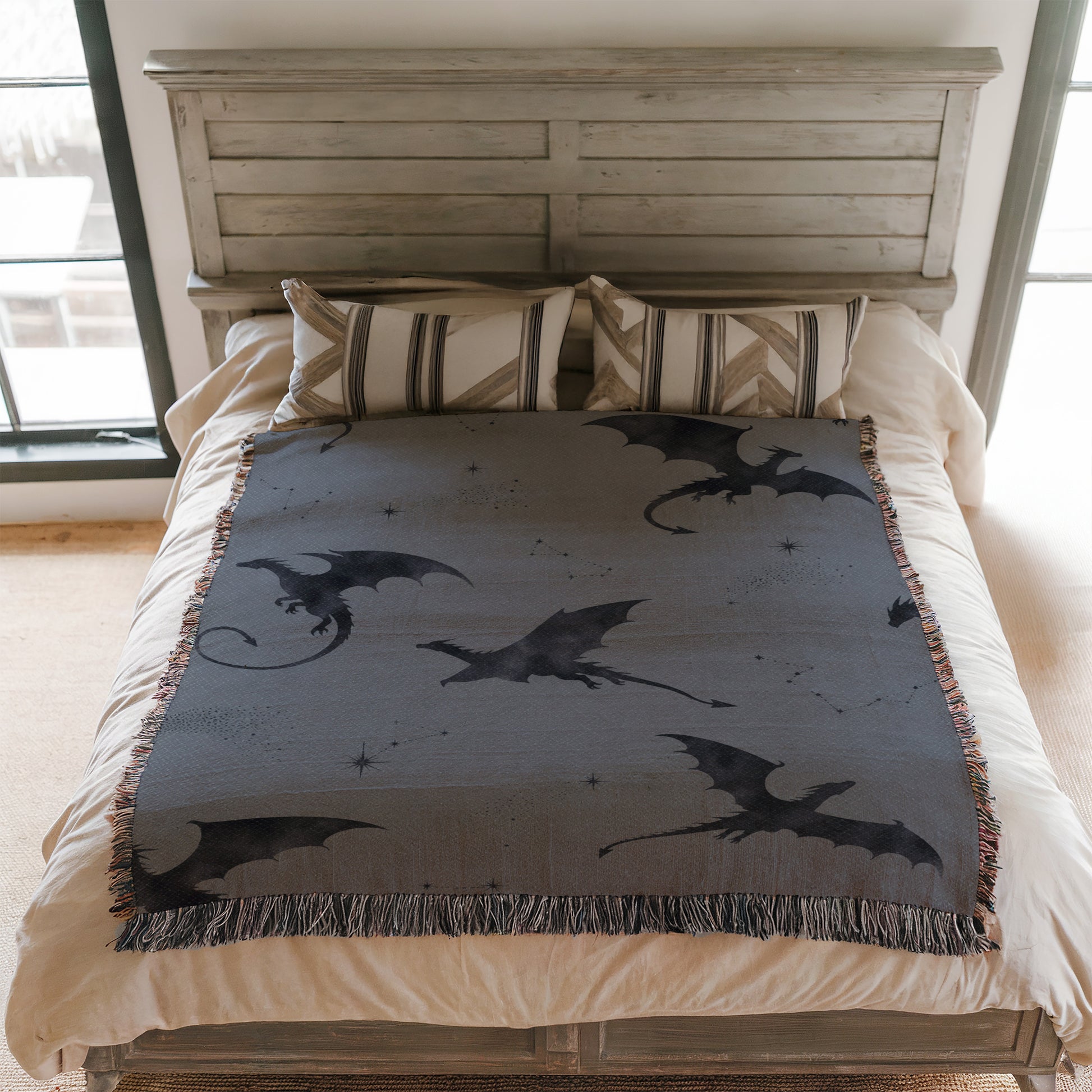 a bedroom with a bed featuring a gray dragon-themed blanket and pillows.