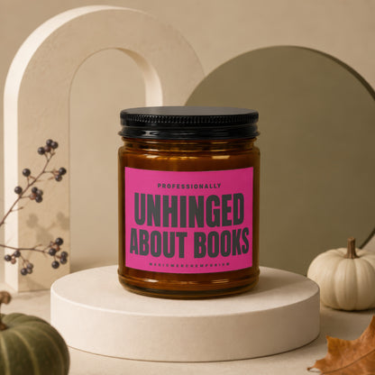 Amber jar candle with pink label reading "Professionally Unhinged About Books".