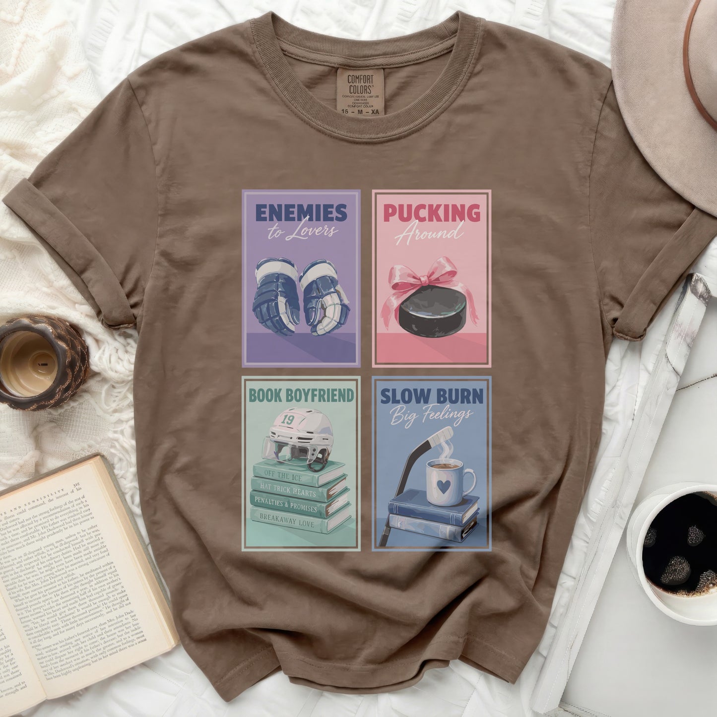 Brown t-shirt with four book cover designs: hockey, romance, and two with text.