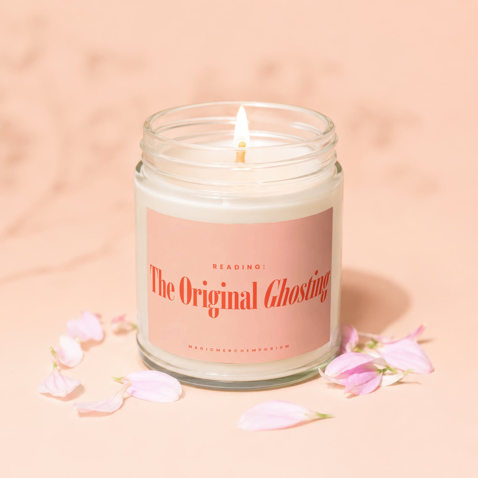 White candle in a glass jar with pink label that reads "The Original Ghosting" and "MAGICMERCHEVMPORIUM".