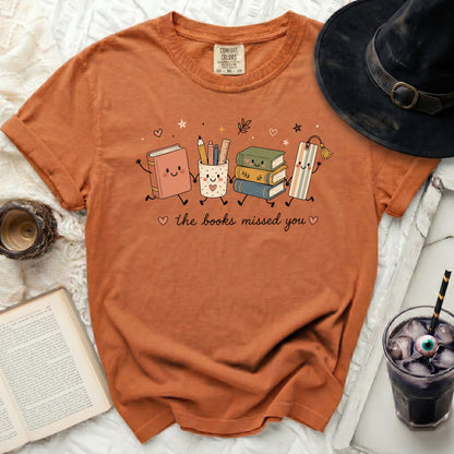 Orange t-shirt with animated books and school supplies that say "the books missed you".