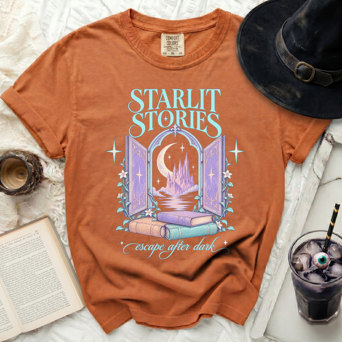 Orange t-shirt with "Starlit Stories" text, castle, moon, and books graphic.