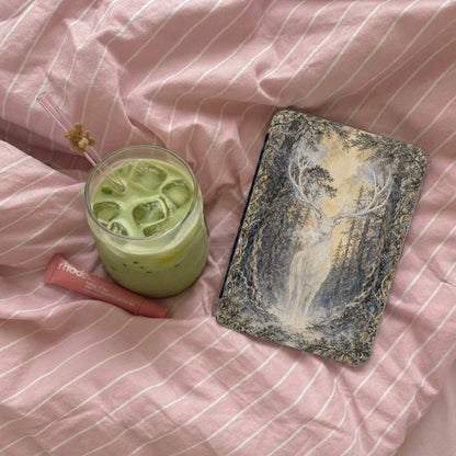 Reindeer in snowy forest art on a phone case with a matcha drink and lip balm.