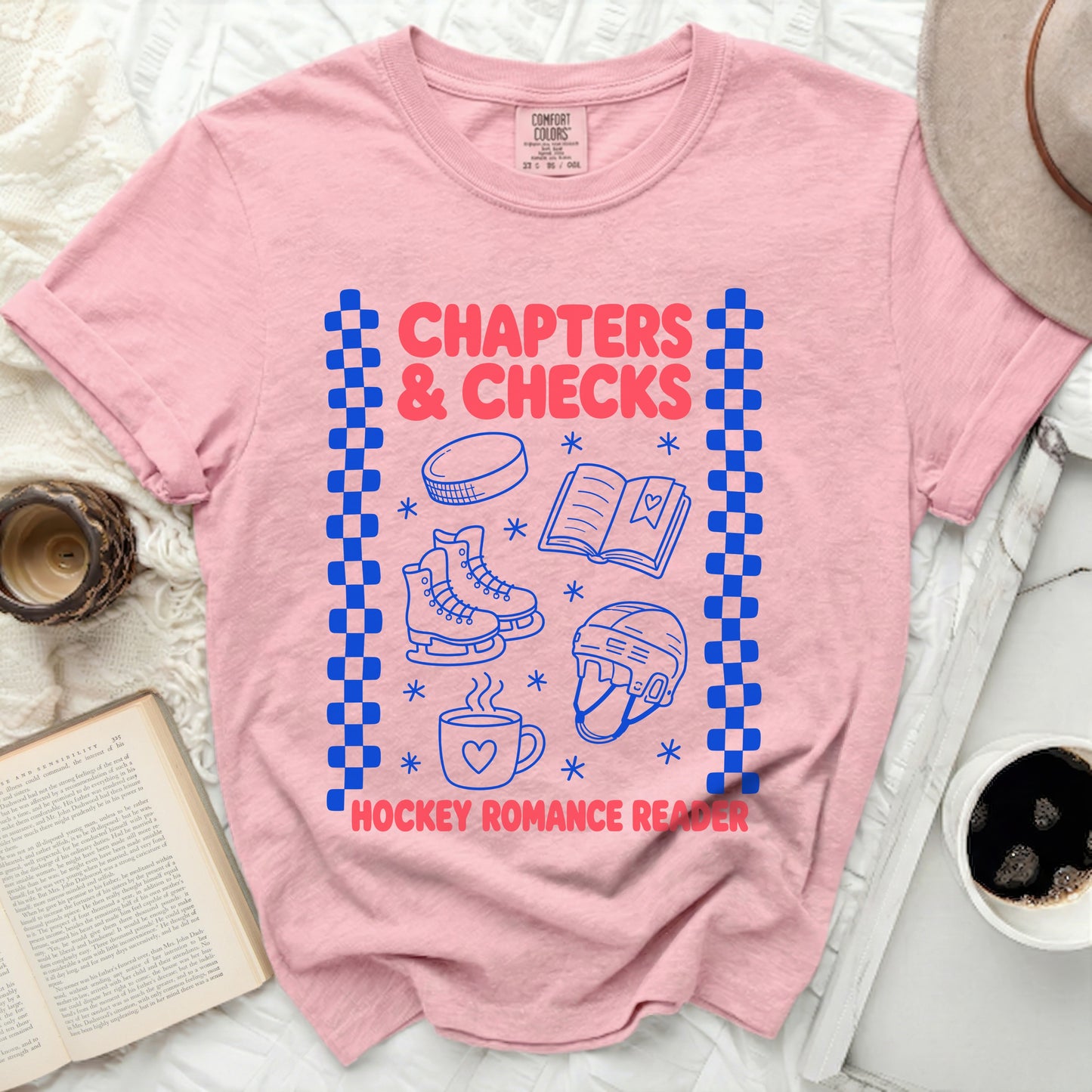 Pink t-shirt with blue checkerboard border and hockey, book, and heart graphics.