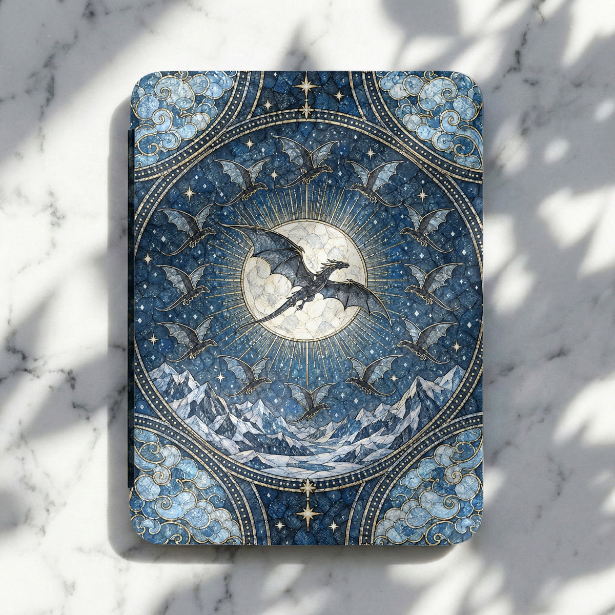 Blue e-reader case featuring a mosaic design of dragons flying around a glowing moon and snowy mountains.