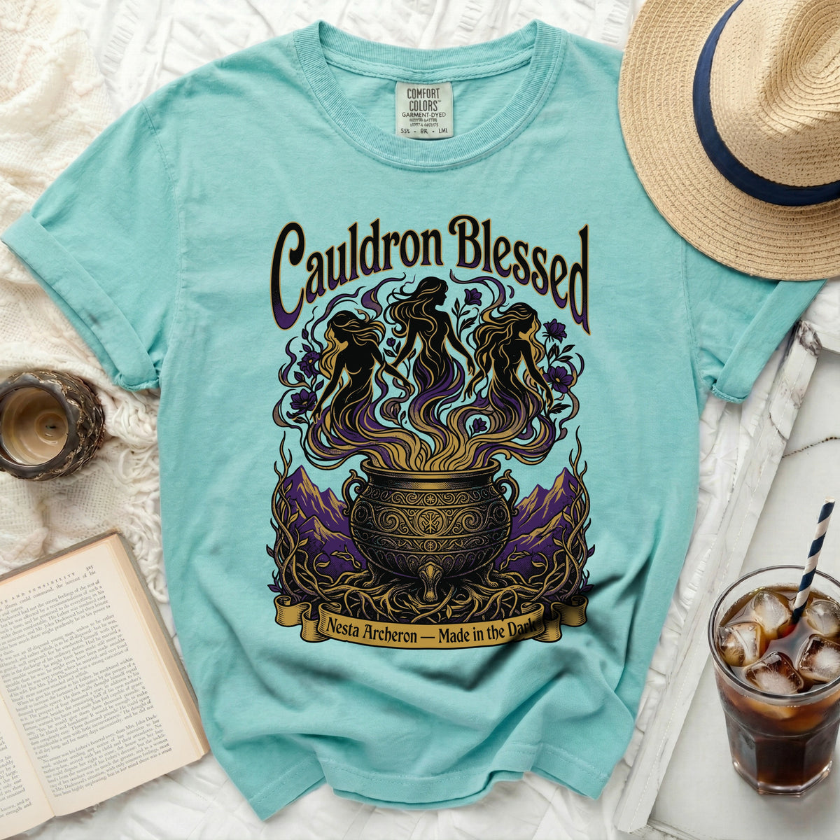 Teal t-shirt with "Cauldron Blessed" and witches graphic, text "Nesta Archeron – Made in the Dark".