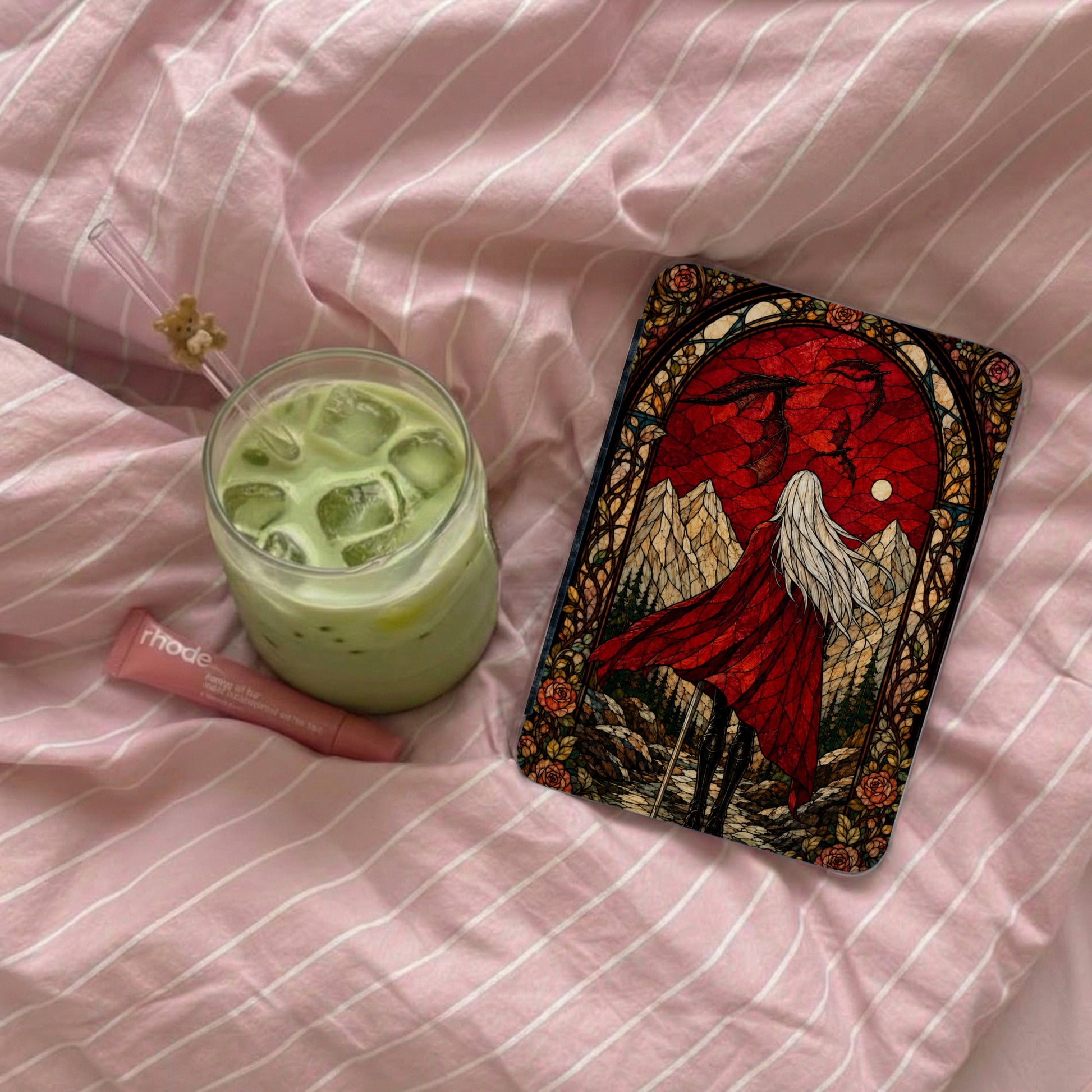 A glass of iced matcha next to a tarot card with a red dragon and a cloaked figure.