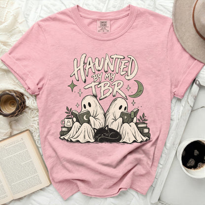 Pink t-shirt with "Haunted by My TBR" text featuring ghosts reading books and a sleeping cat.