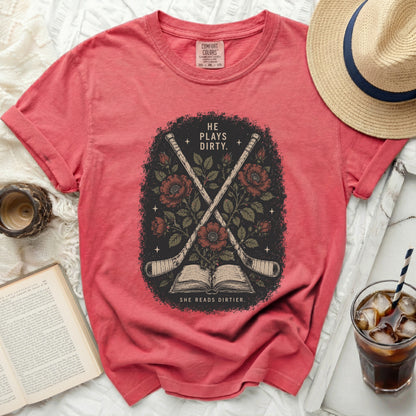 Red t-shirt with crossed hockey sticks and roses, text "HE PLAYS DIRTY. SHE READS DIRTIER."