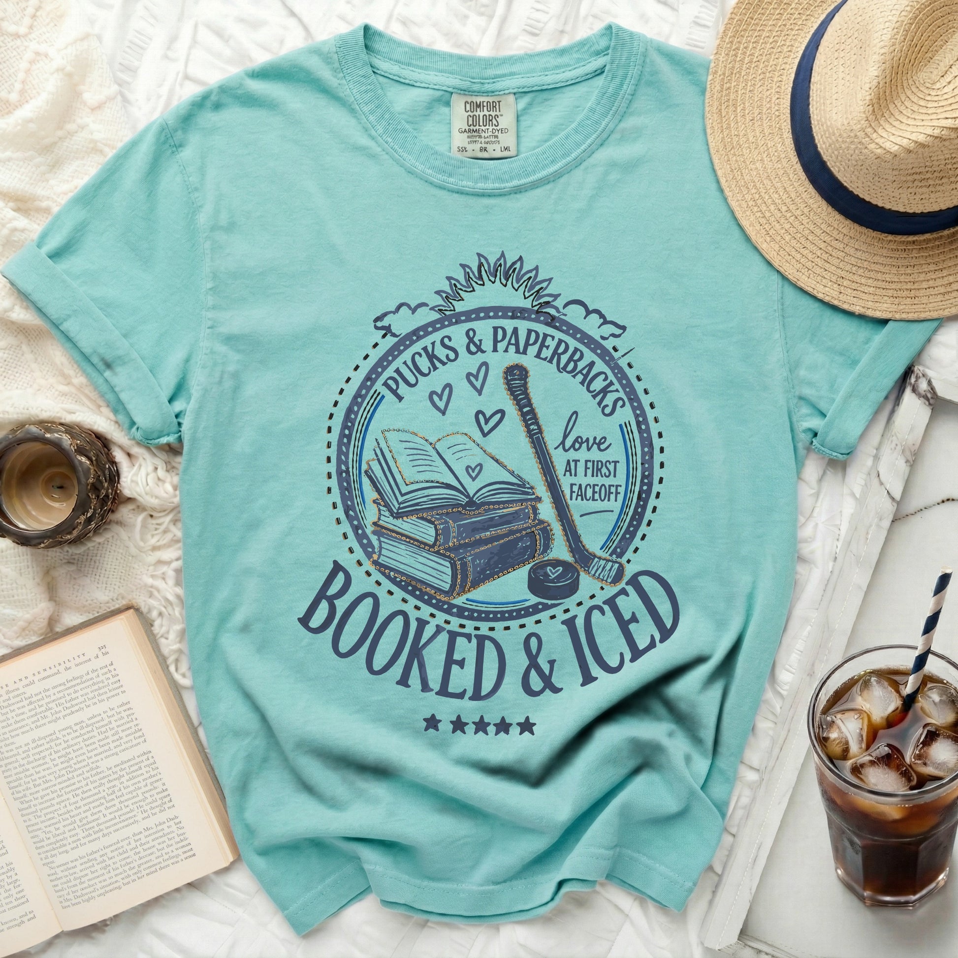 T-shirt with "Pucks & Paperbacks Booked & Iced" text and hockey elements.
