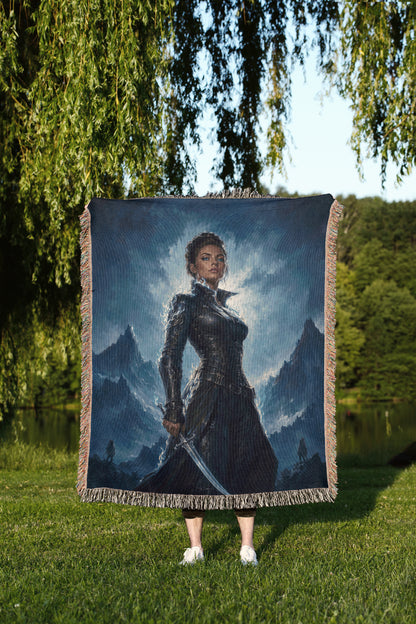A person is standing in a grassy area, holding a large tapestry or blanket that features a painting of a woman in a dark outfit.