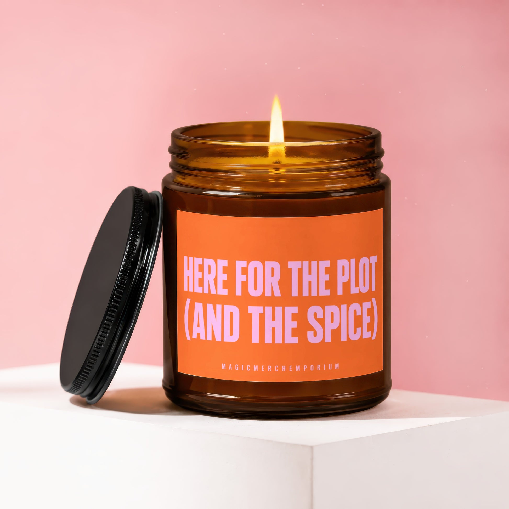 Amber jar candle with "HERE FOR THE PLOT (AND THE SPICE)" text on orange label.