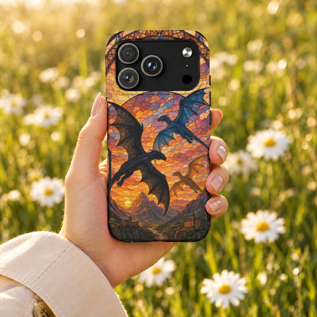 A hand holds a smartphone with a stained-glass style dragon design case against a blurry meadow background.