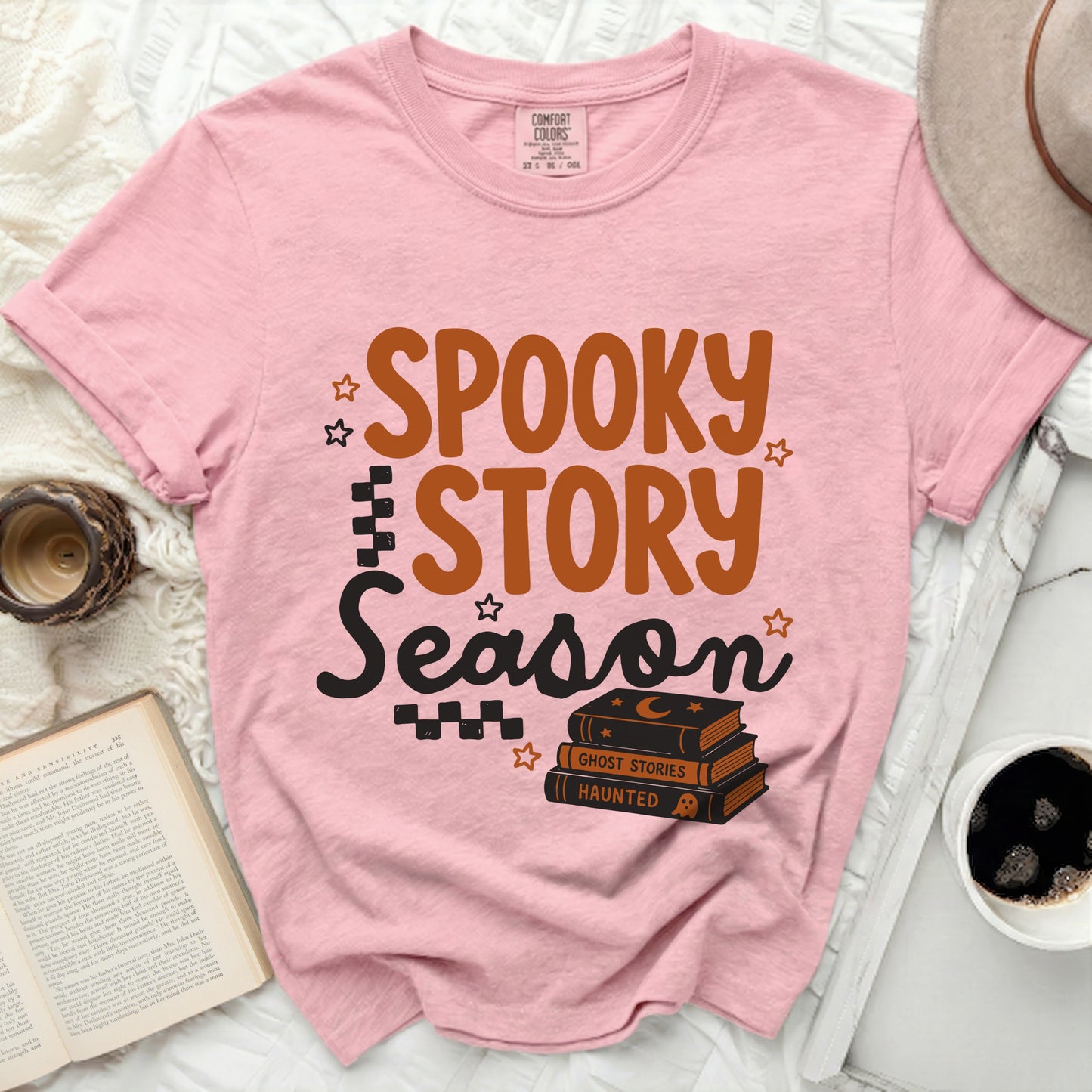 Pink t-shirt with "Spooky Story Season" graphic and stacked books.