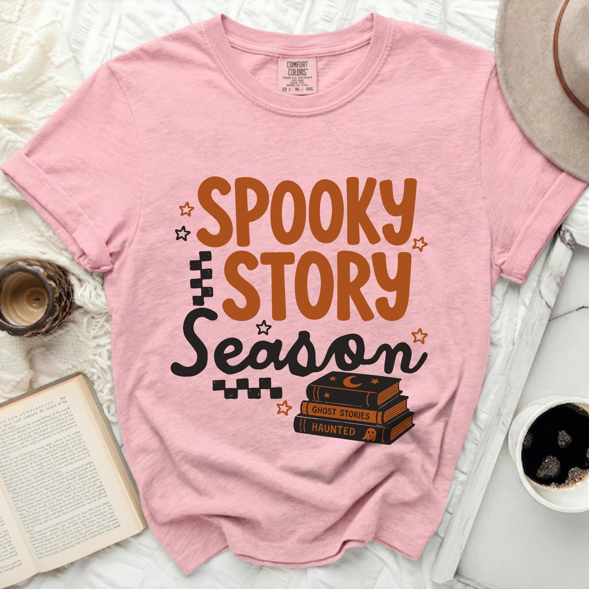 Pink t-shirt with "Spooky Story Season" graphic and stacked books.