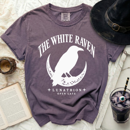 Purple t-shirt with white graphic of a raven on a crescent moon and text.
