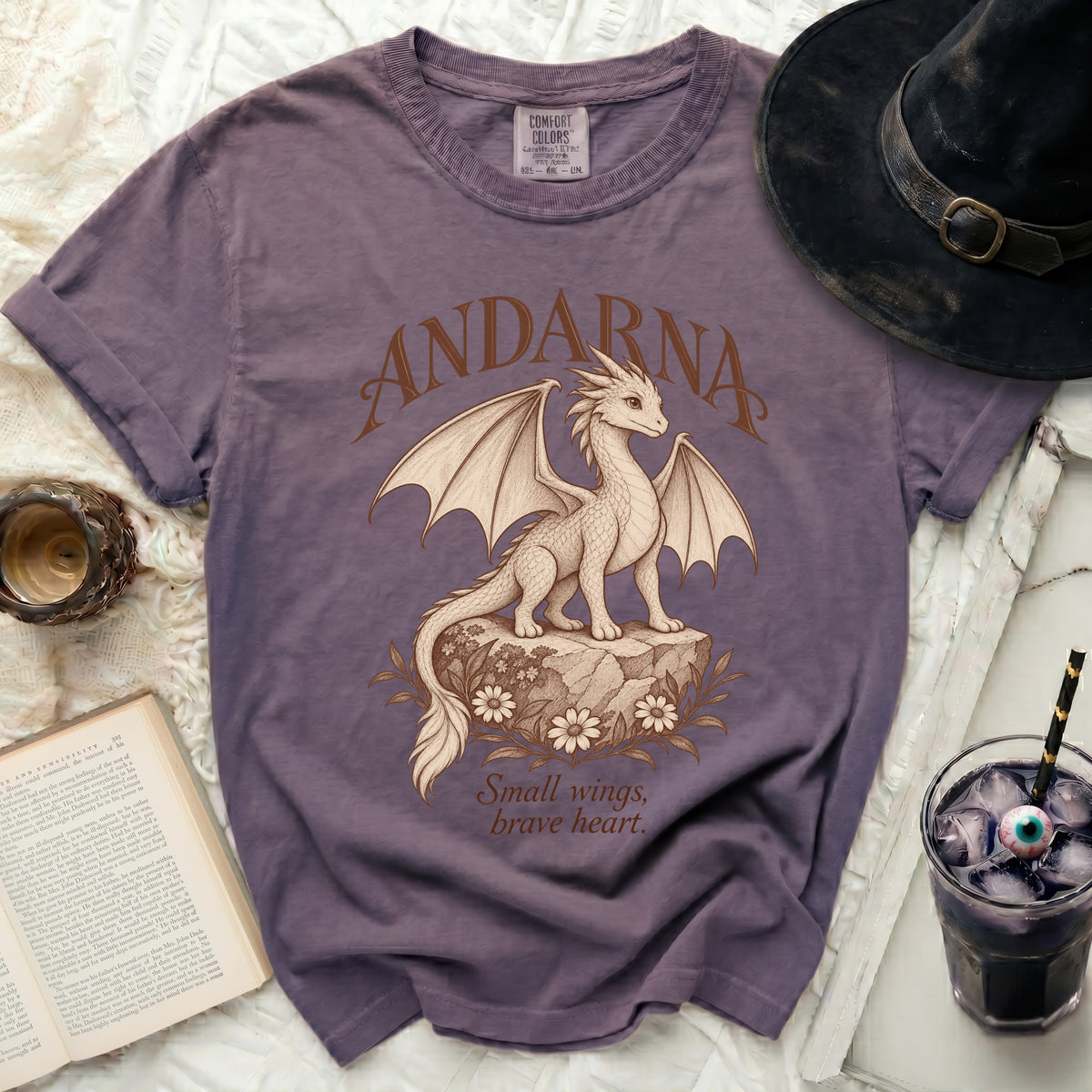 Purple t-shirt with "Andarna" and a dragon graphic, text "Small wings, brave heart."