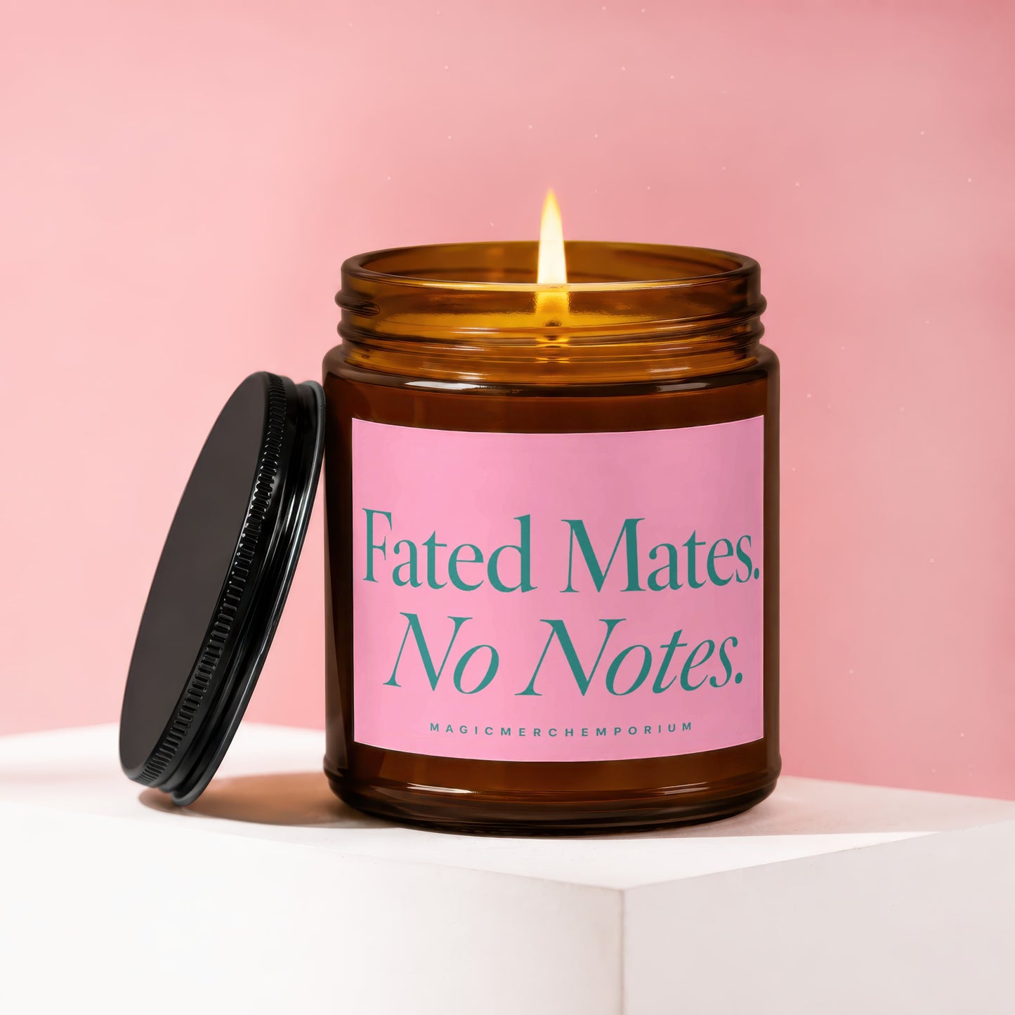 Amber jar candle with lit flame and pink label reading "Fated Mates. No Notes."