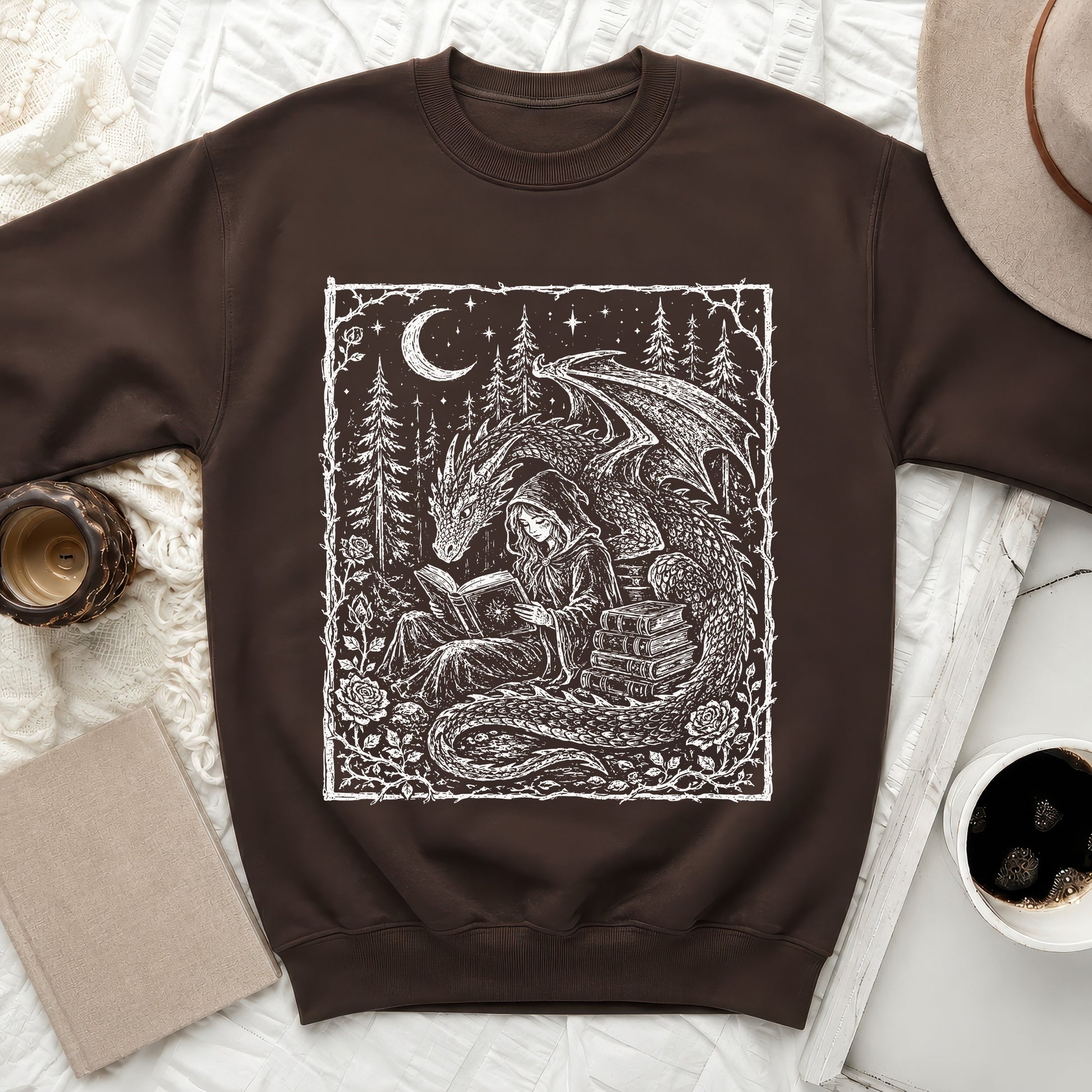 Brown sweatshirt with a fantasy art print of a woman reading by a dragon.
