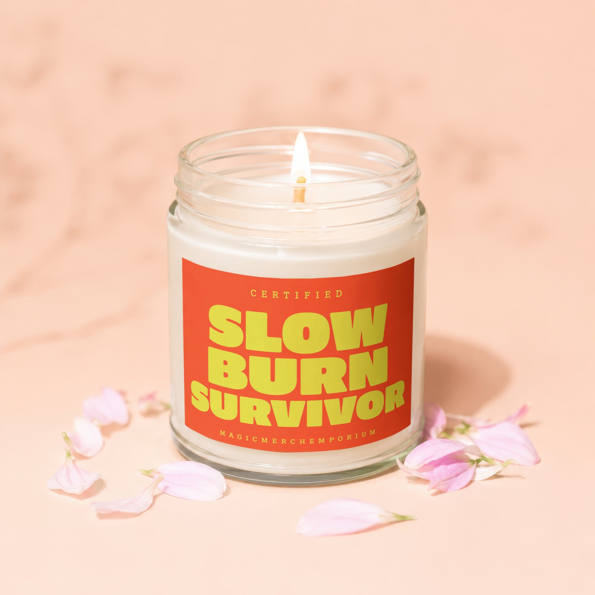 Candle with "Slow Burn Survivor" and "Magic Merch Emporium" text on an orange label.