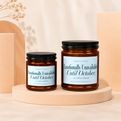 Two amber glass candles with black lids labeled "Emotionally Unavailable Until October."