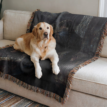 A golden retriever dog is lying on a black and gray patterned blanket on a beige couch.