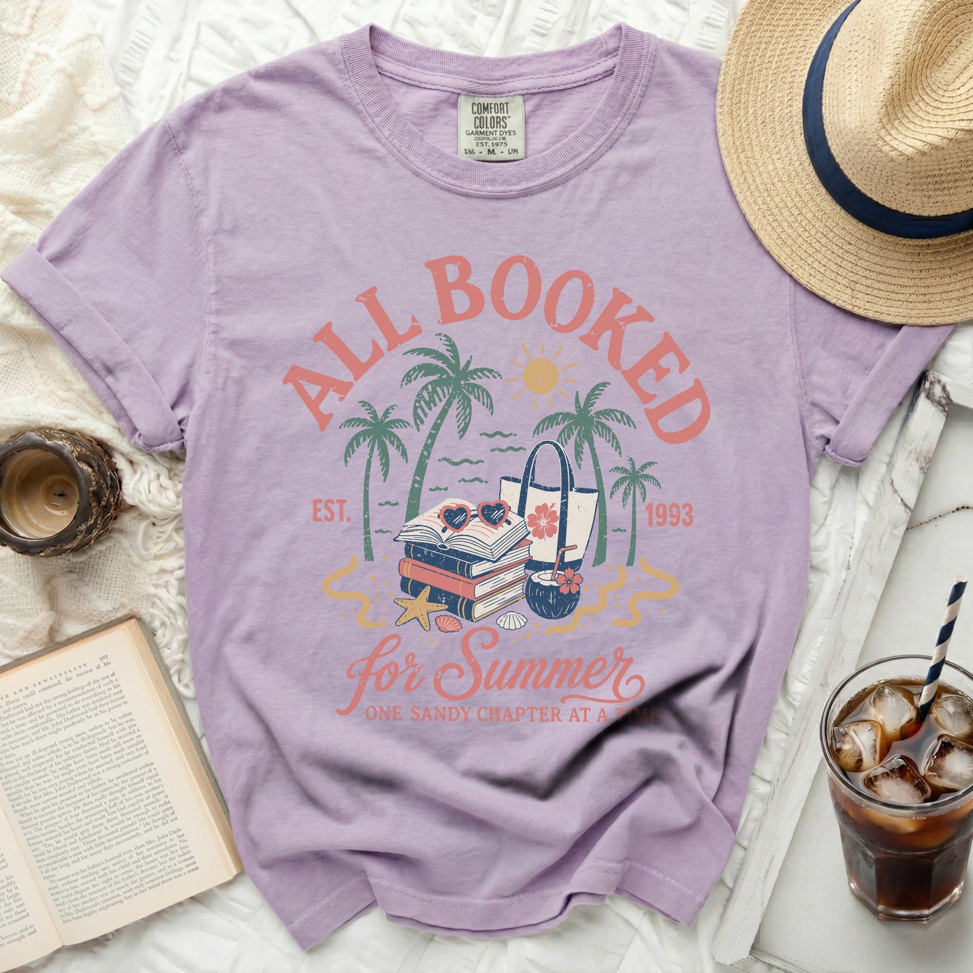 Purple t-shirt with "All Booked for Summer" text and summer graphics.