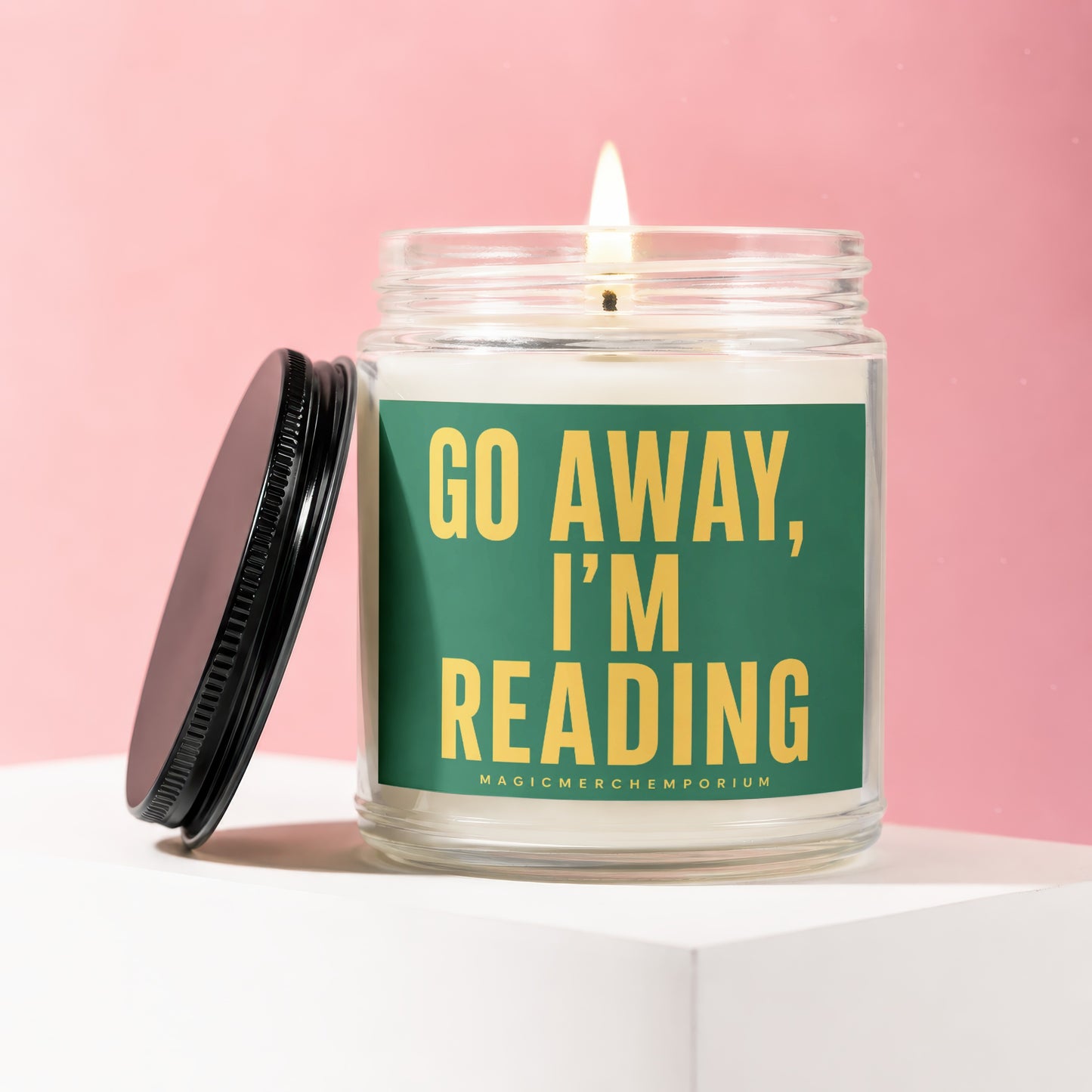 Lit glass candle with green label reading "GO AWAY, I'M READING".