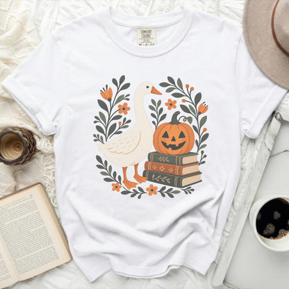 White t-shirt with a goose, pumpkin, and books graphic surrounded by flowers.