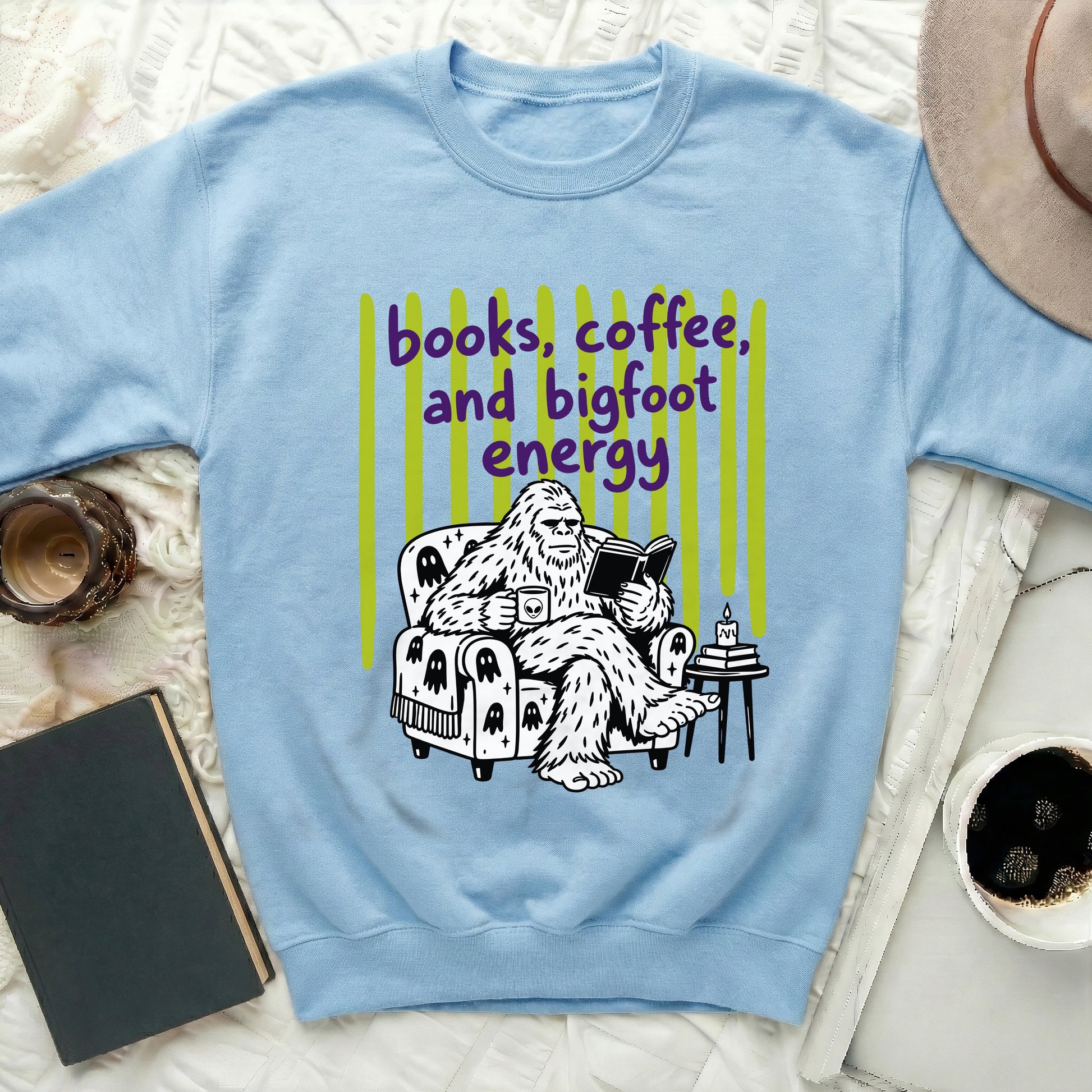 Light blue sweatshirt with graphic of Bigfoot reading and drinking coffee.