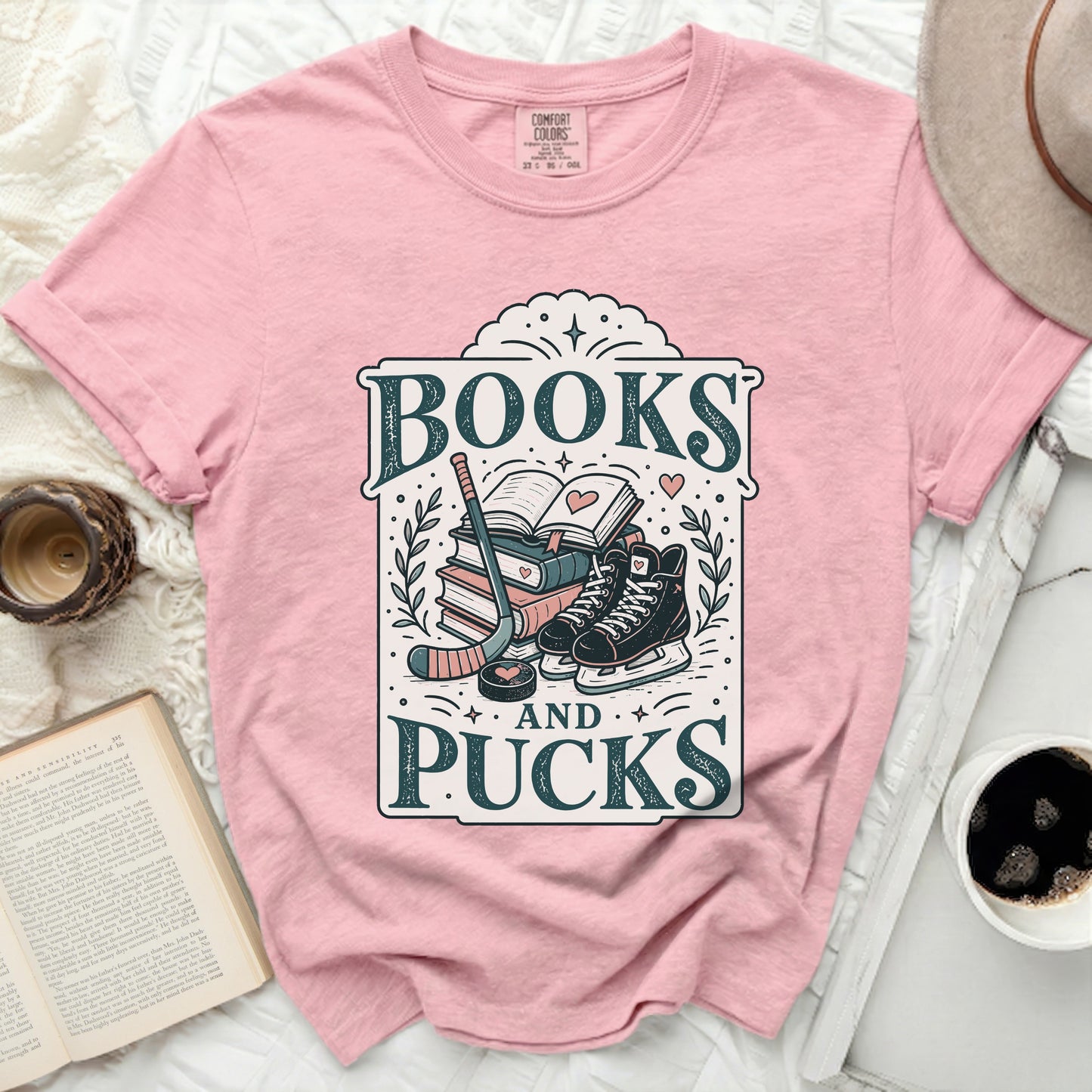 Pink t-shirt with "Books and Pucks" text and hockey gear illustration.