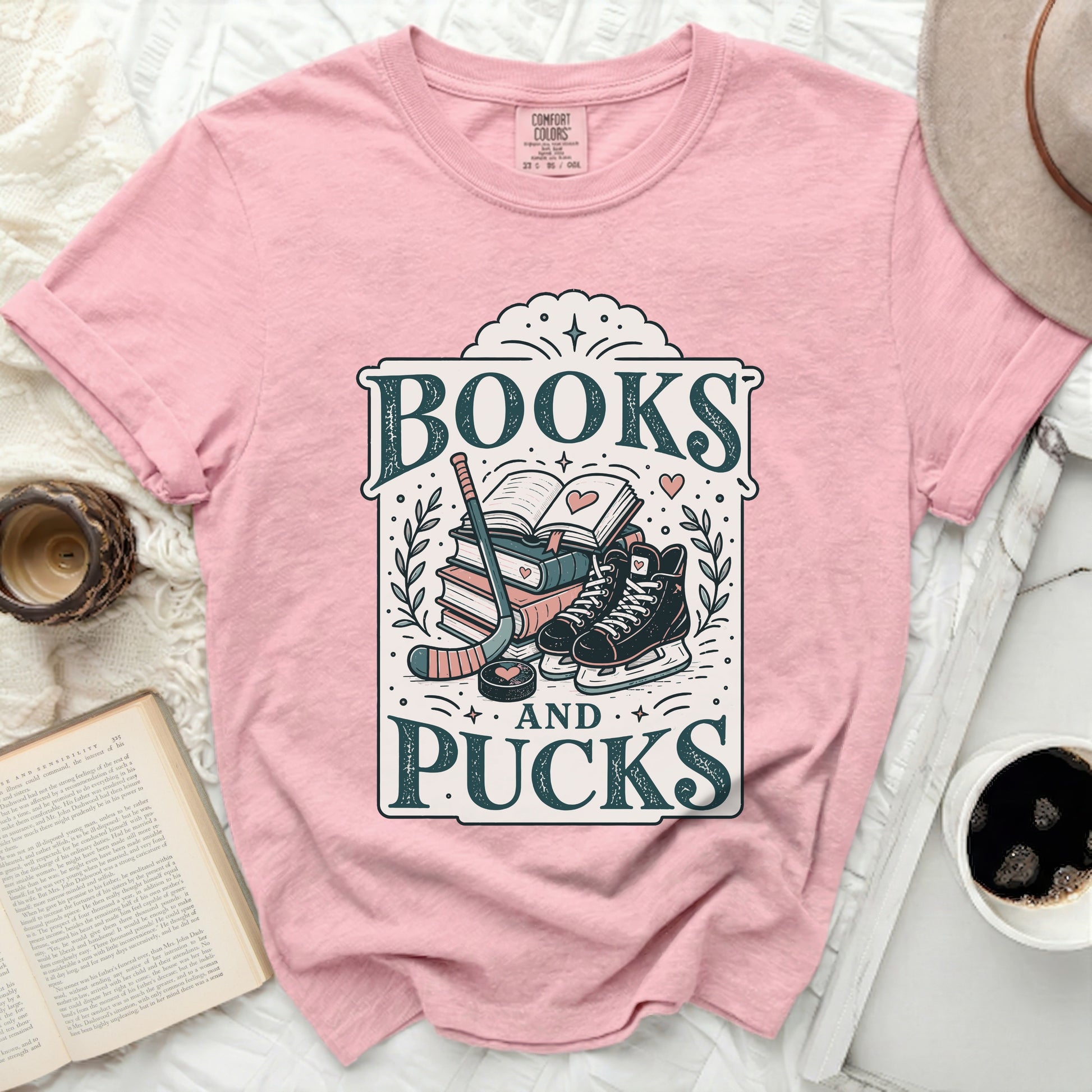 Pink t-shirt with "Books and Pucks" text and hockey gear illustration.
