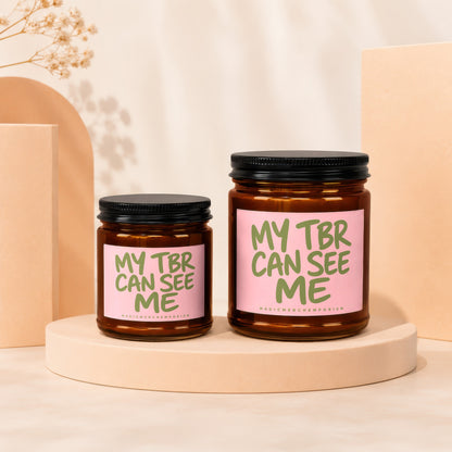 Two amber glass candles with pink labels reading "MY TBR CAN SEE ME" and "MAGICMERCHEMPORIUM".