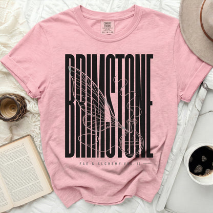Pink t-shirt with black "BRIMSTONE FAE & ALCHEMY VOL. II" text and winged vial graphic.
