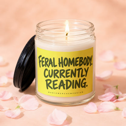 Jar candle with a lit wick and a yellow label reading "Feral Homebody Currently Reading."