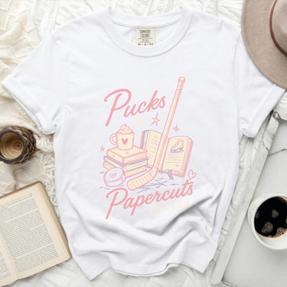 White t-shirt with "Pucks Papercuts" hockey and book graphic.