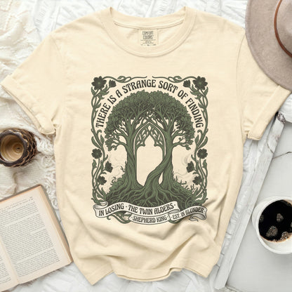 T-shirt with twin alder trees and quote "There is a strange sort of finding".
