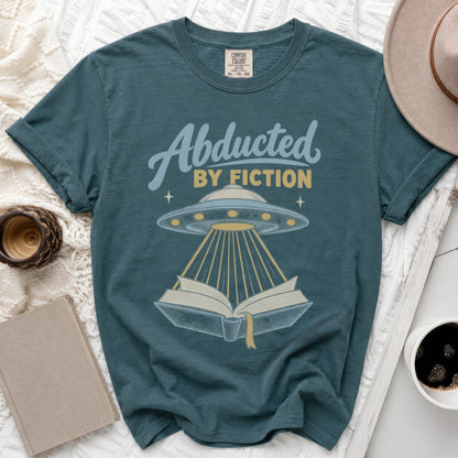Teal t-shirt with "Abducted BY FICTION" text, UFO, and open book graphic.