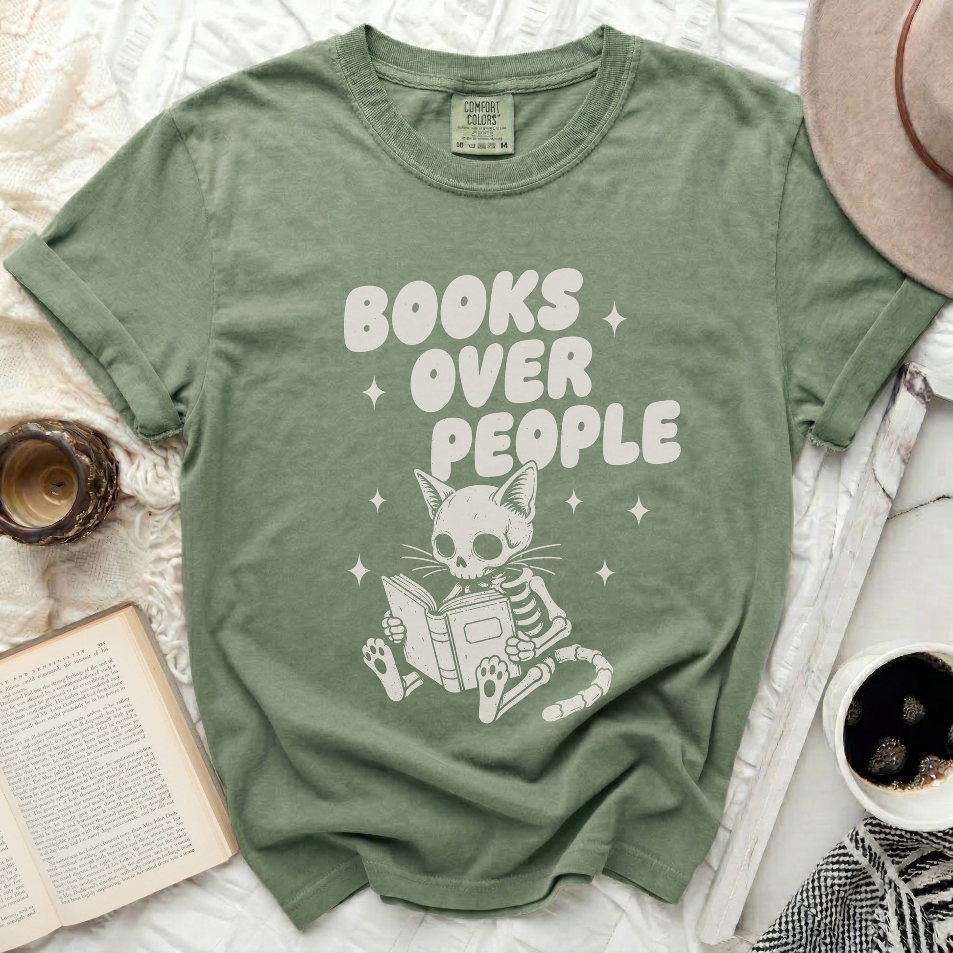 Olive green t-shirt with white text "BOOKS OVER PEOPLE" and skeleton cat reading book.
