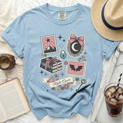 Light blue t-shirt with "Night Court" graphic and fantasy illustrations.