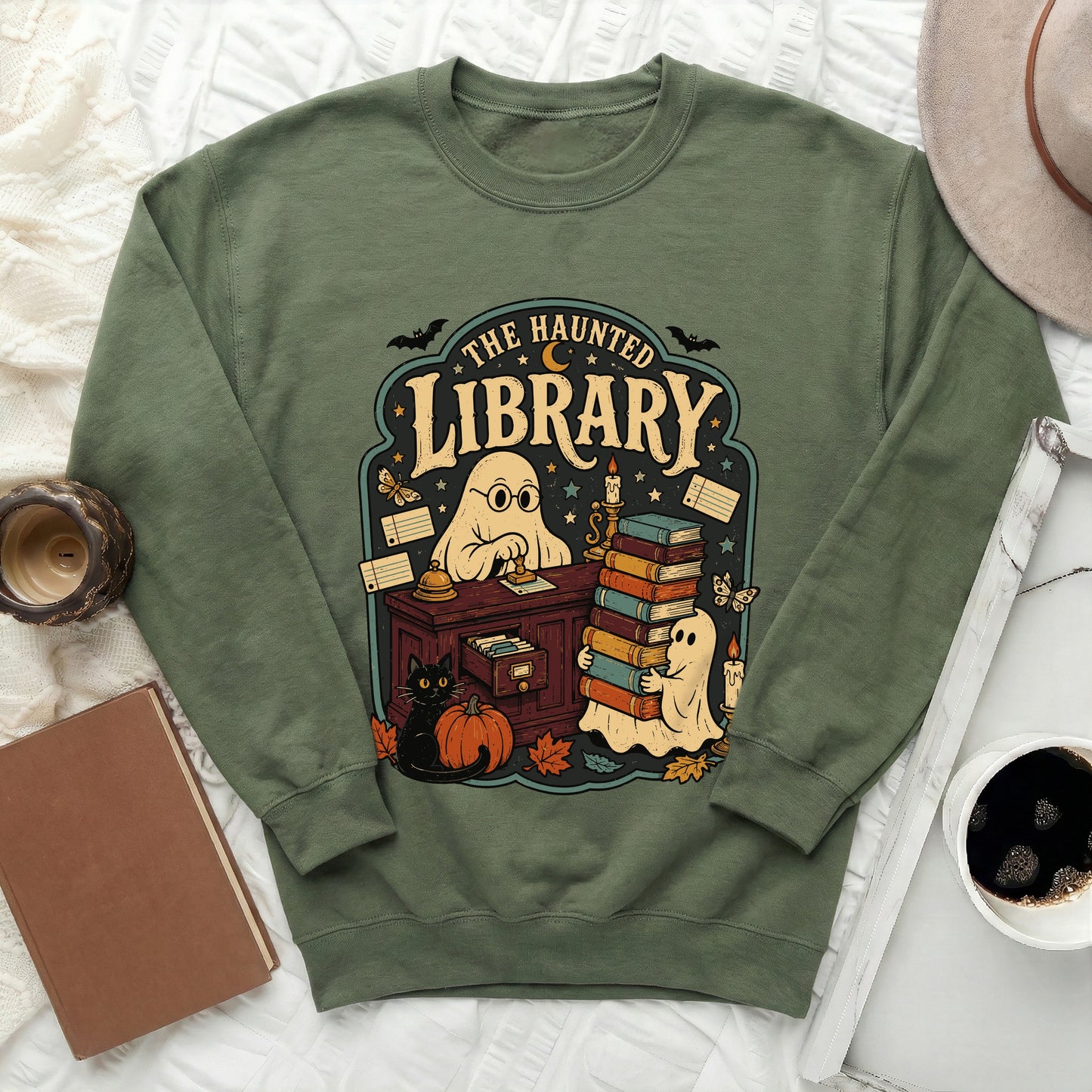 Green sweatshirt with a haunted library graphic featuring ghosts, books, and a black cat.