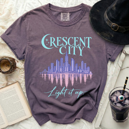 Purple t-shirt with "Crescent City Light it up" text and skyline graphic.