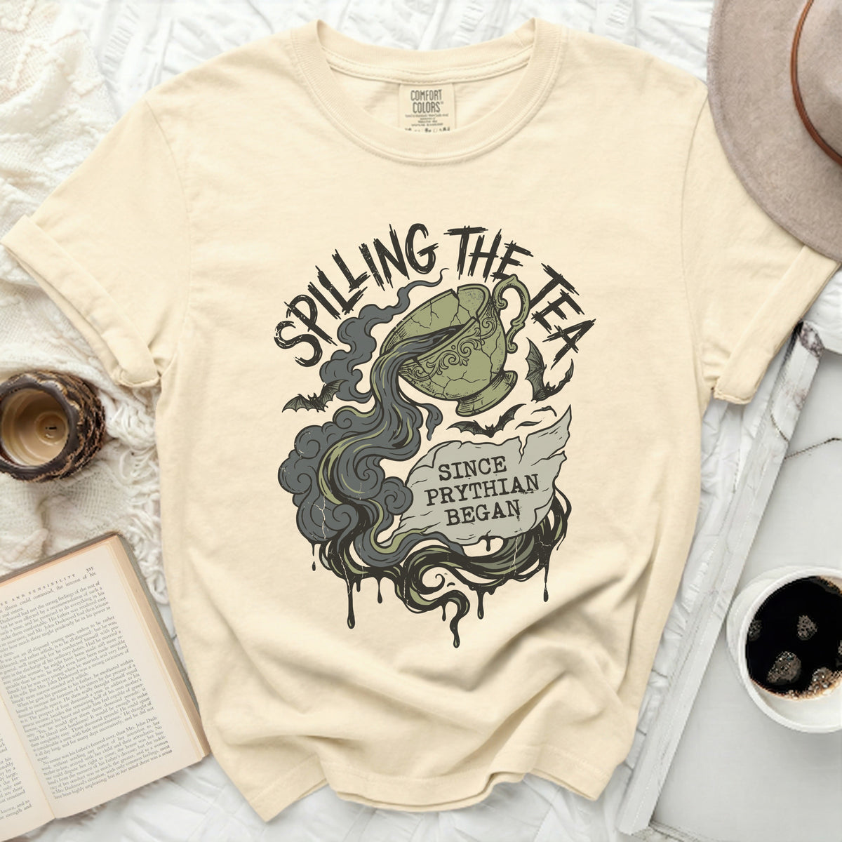 Cream t-shirt with "Spilling the Tea Since Pythian Began" graphic.