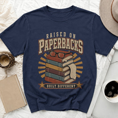 Navy t-shirt with graphic of stacked books, glasses, and text "Raised on Paperbacks Built Different".