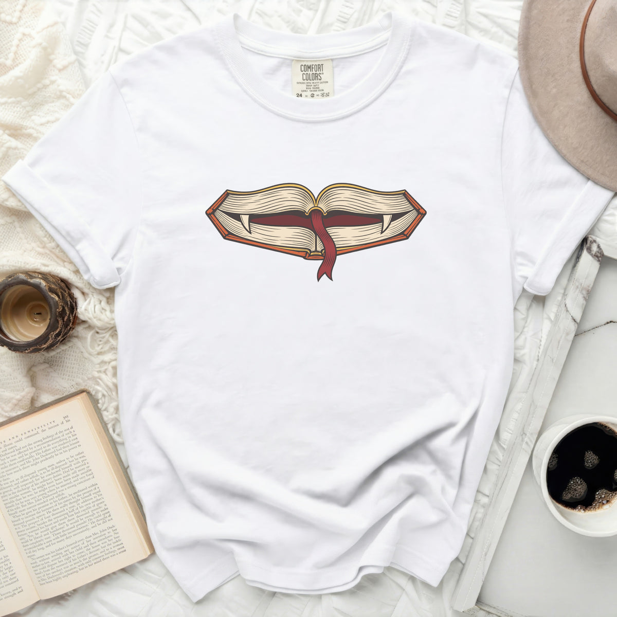 White t-shirt with an open book design featuring fangs and a ribbon.