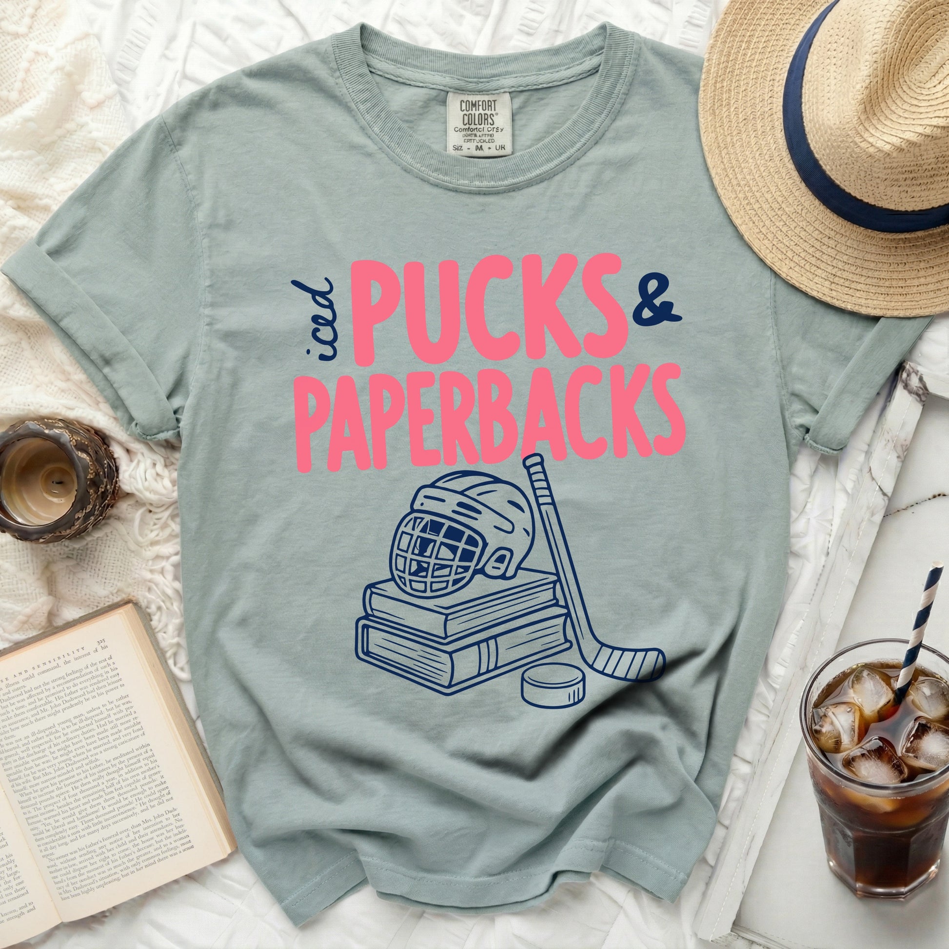 T-shirt with "iced PUCKS & PAPERBACKS" graphic and hockey gear.