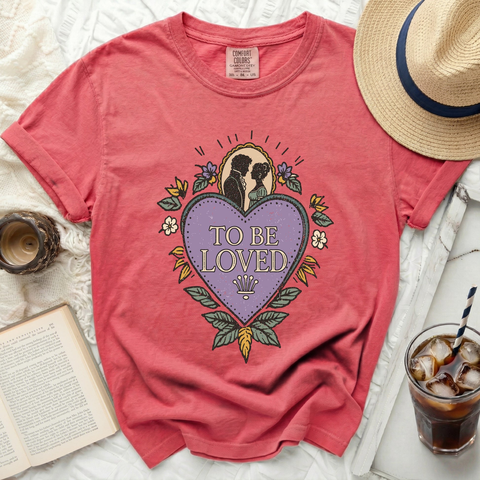 Salmon t-shirt with "To Be Loved" graphic featuring a couple and heart.