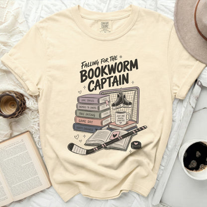 Cream graphic t-shirt with "Falling for the Bookworm Captain" text and hockey elements.