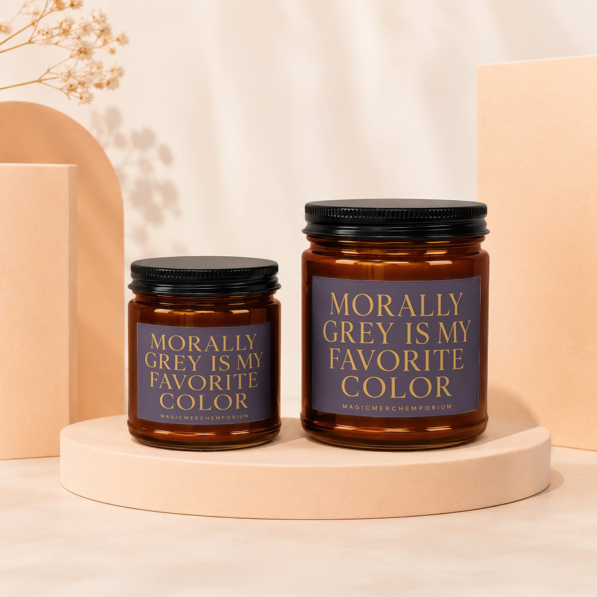Two amber glass candles with black lids and "Morally Grey Is My Favorite Color" labels.
