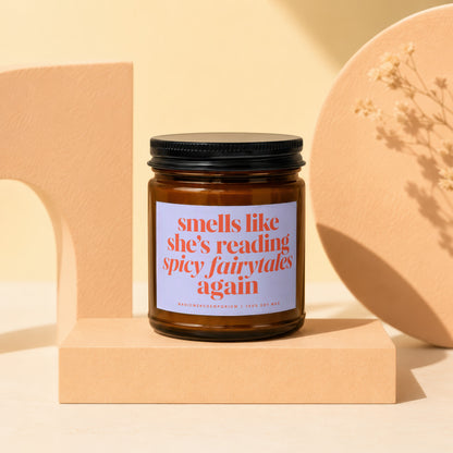 Candle with black lid, label reads "smells like she's reading spicy fairytales again"